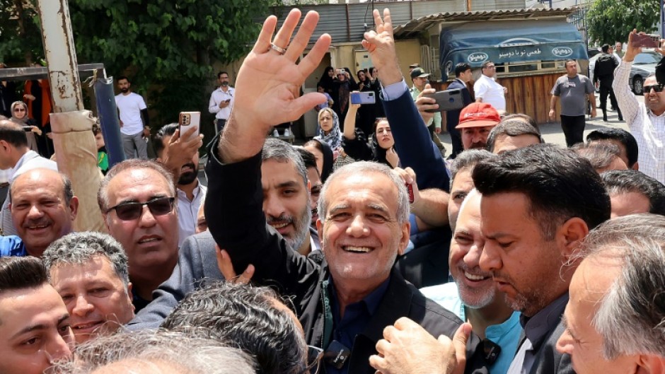 Reformist candidate Masoud Pezeshkian waves to supporters outside a polling station in Tehran