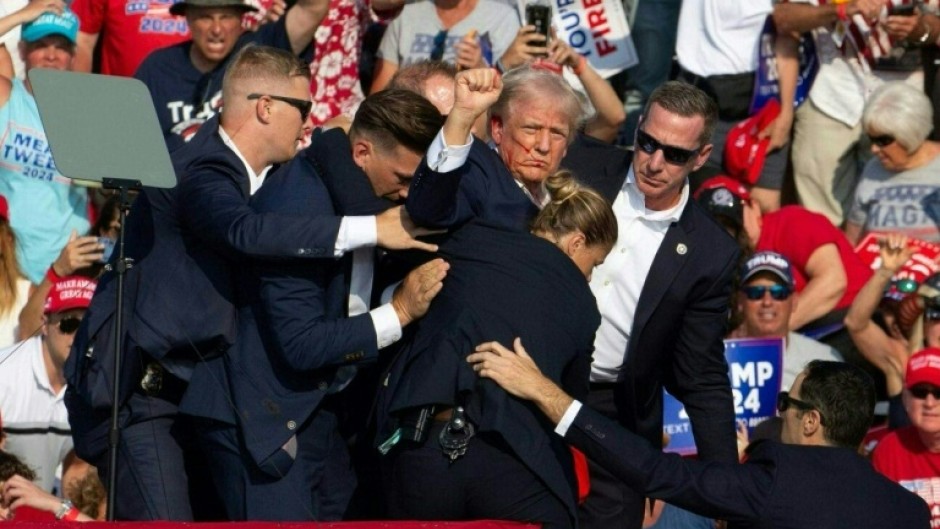 Trump is seen with blood on his face as Secret Service rush him off the stage