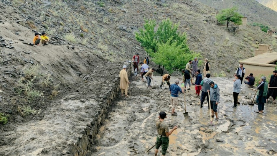 Afghan residents shovel mud following flash floods after heavy rainfall at Pesgaran village in Dara district