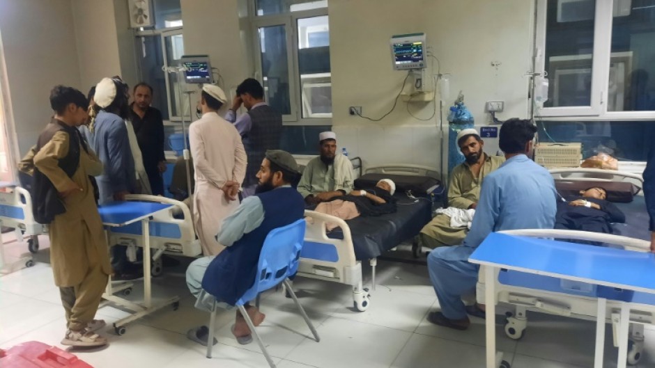 Men sit next to injured children as they receive treatment at a hospital in Jalalabad 