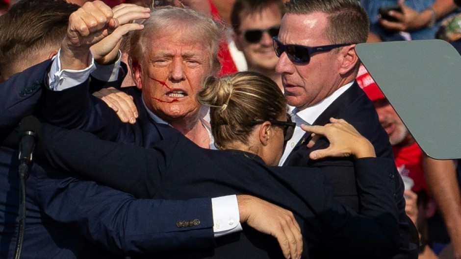 Donald Trump is seen with blood on his face surrounded by Secret Service agents as he is taken off the stage in Pennsylvania, on July 13, 2024