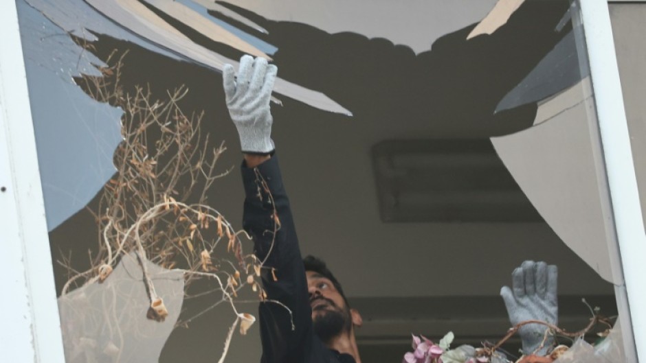 An Israeli policeman collects glass shrapnel from the window of a building damaged in the Tel Aviv drone strike