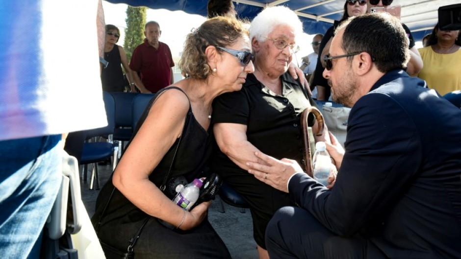 Cypriot President Nikos Christodoulides (R) talks with  the widow of a soldier killed in the 1974 Turkish invasion of Cyprus, at Makedonitissa military cemetery in Nicosia, 