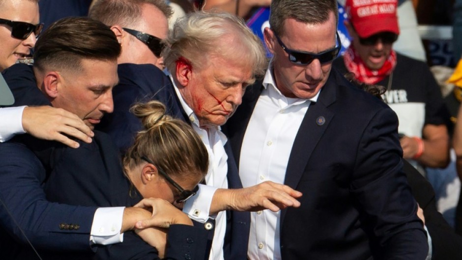 Secret Service agents shield former president Donald Trump as he is escorted off the stage following an attempted assassination