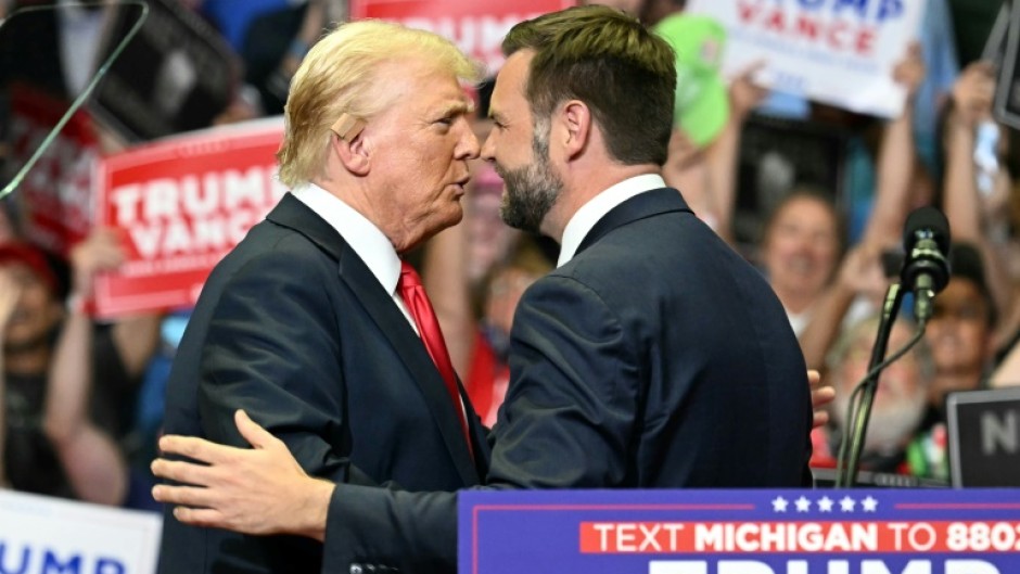 Republican nominee Donald Trump, wearing a new bandage on his ear after an attempted assassination, greets running mate J.D. Vance at a rally in Grand Rapids, Michigan