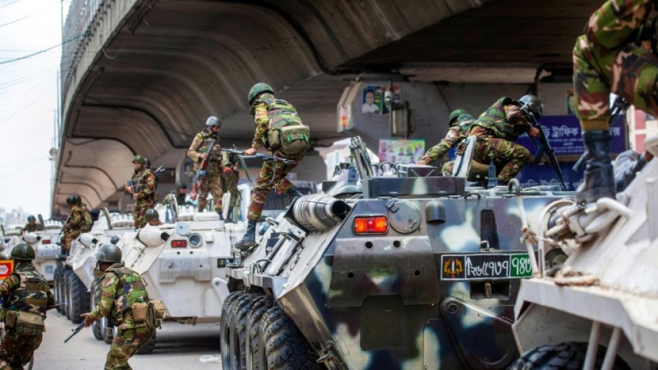 Bangladesh troops disembark armoured vehicles as they patrol the streets of the capital