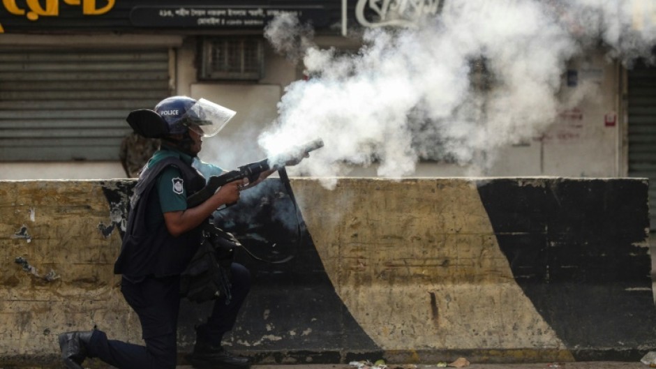 A Bangladesh policeman fires tear gas shells at protesters during clashes in Dhaka