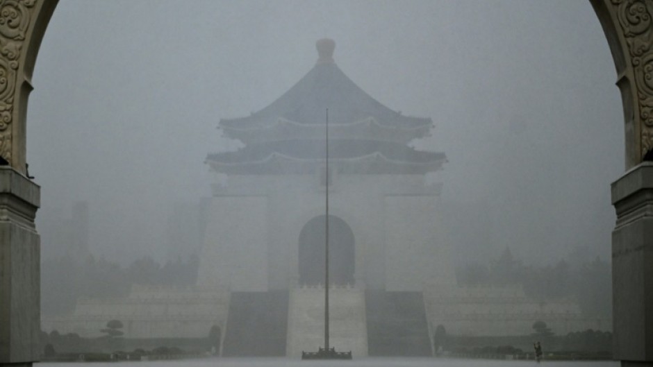 A visitor takes photographs in front of the Chiang Kai-shek Memorial Hall in heavy rain caused by Typhoon Gaemi in Taipei