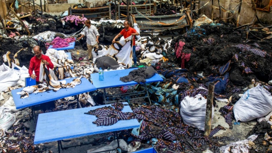 Workers sort through the remains of a garment factory torched during the protests