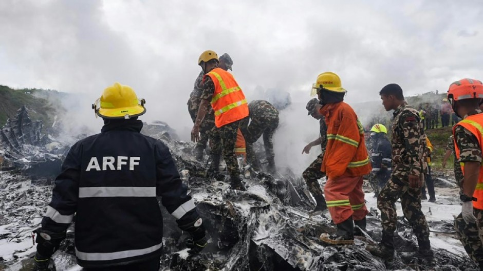 Rescuers and army personnel stand at the site after a Saurya Airlines' plane crashed during takeoff at Tribhuvan International Airport in Kathmandu on July 24, 2024