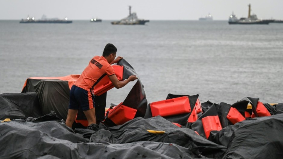 A coast guard staffer arranges an oil spill containment boom to be use3d in Manila Bay