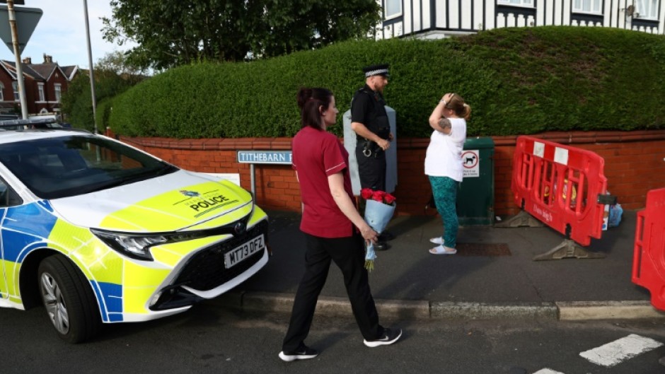 A woman arrives with a floral tribute to pay her respects at Hart Street in Southport, northwest England, on July 29, 2024, following a knife attack