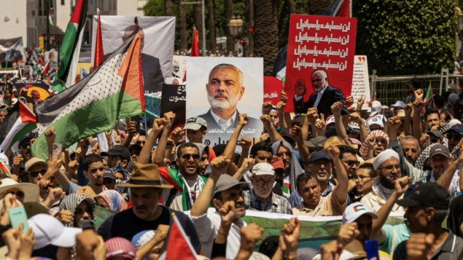 Demonstrators lift placards with Ismail Haniyeh's image and Palestinian flags during a rally in Rabat, Morocco