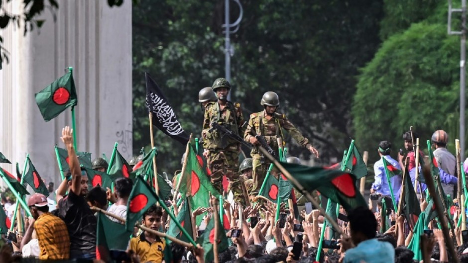 Bangladeshi protesters gather near the gates of ousted premier Sheikh Hasina as soldiers watch: Hasina, 76, fled the country by helicopter