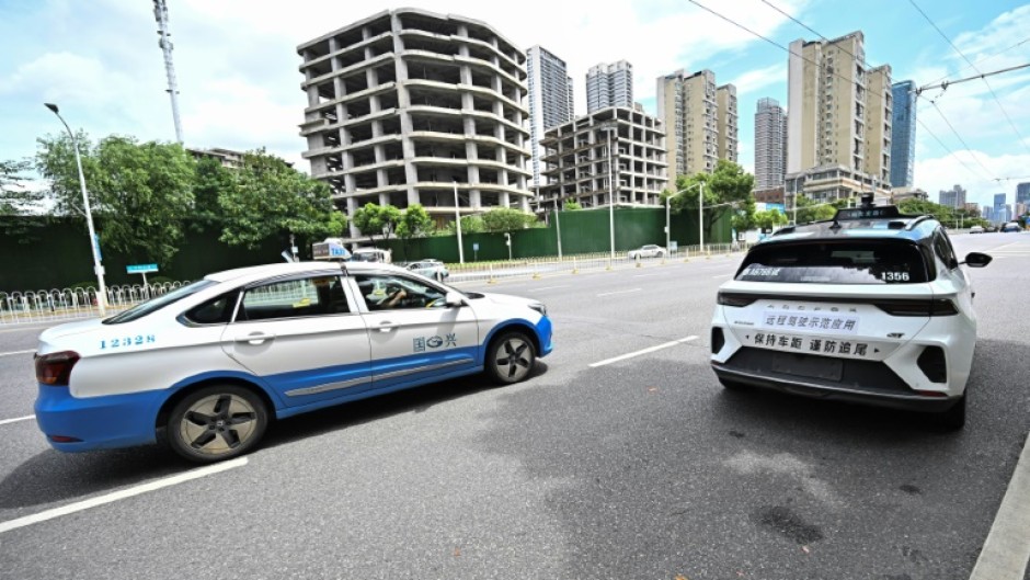 A regular taxi overtakes a driverless one in Wuhan, home to one of the world's largest robotaxi networks