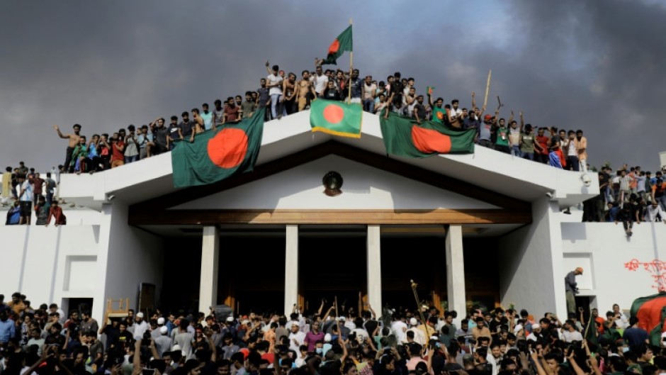 Protesters display Bangladesh's national flag as they storm Sheikh Hasina's palace