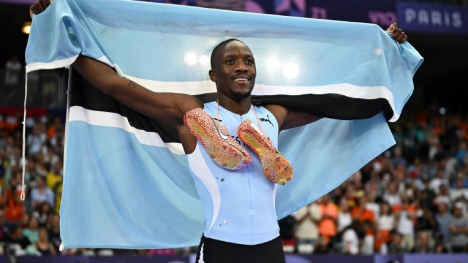 Letsile Tebogo poses with the Botswana flag after a stunning run to win 200m gold at the Paris Olympics 