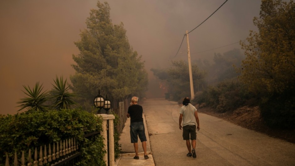 Local residents watch a wildfire in Dione outside Athens