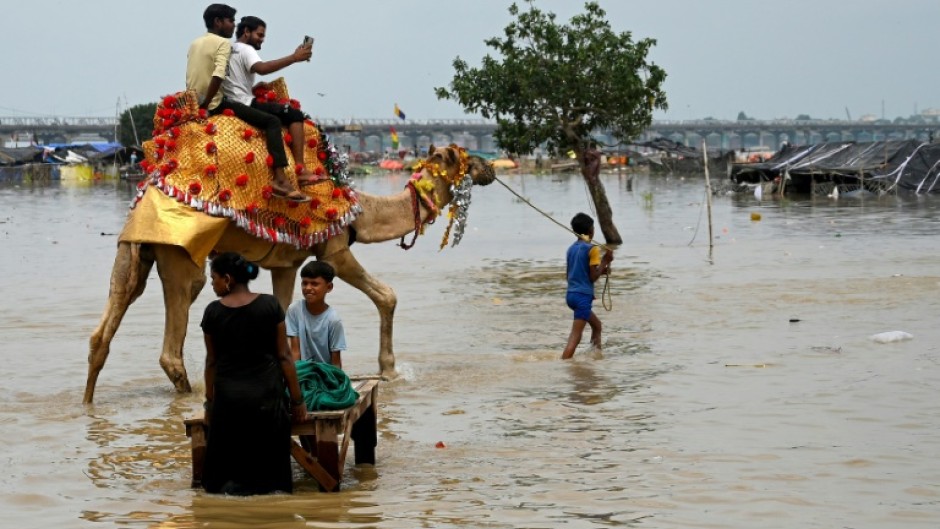 Men riding a camel across  a flooded field on the banks of river Ganges in India on August 6