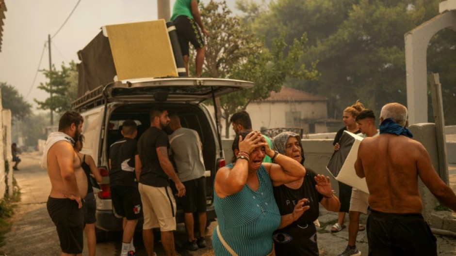 Residents cry as they try to save belongings from homes in Penteli, one of the Athens suburbs worst hit by a wildfire that forced the evacuation of thousands of people