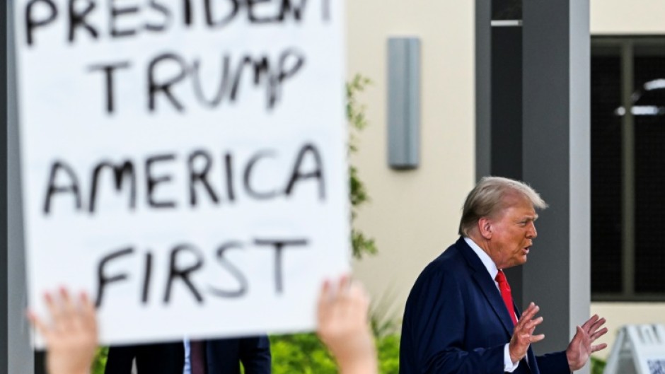 A supporter holds up a sign as former US President and Republican presidential candidate Donald Trump leaves after casting his vote in Florida's primary election on August 14, 2024 in West Palm Beach, Florida