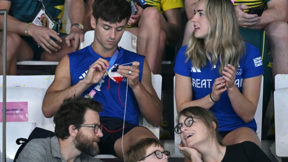 When he wasn't in the pool at the Olympics, Britain's Tom Daley (L) was spotted enjoying the Games from the stands while knitting