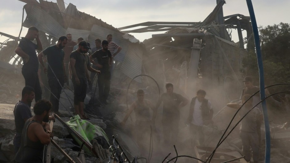 Palestinians inspect the site of an Israeli strike in Al-Zawaida, central Gaza, which the civil defence agency said killed 15 people from a Palestinian family