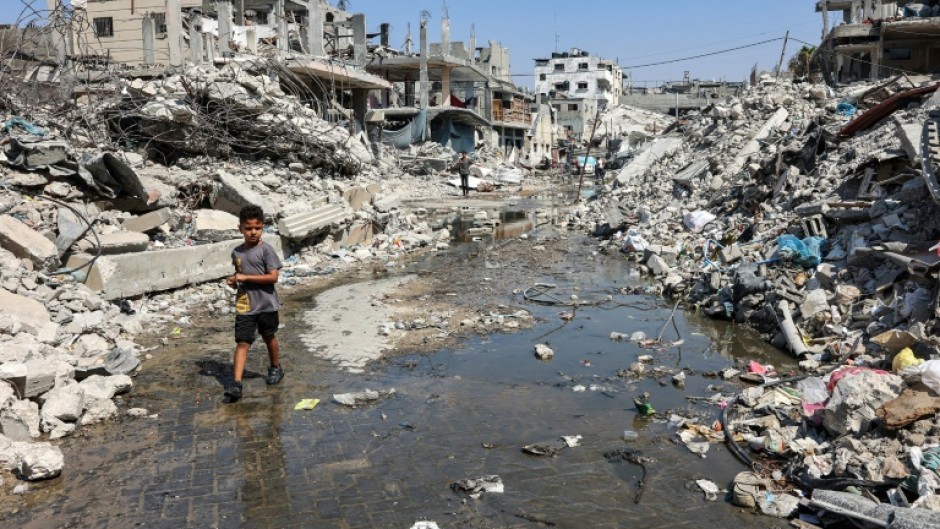 In scorching weather, a boy walks through a puddle of sewage water surrounded by mounds of garbage and rubble in Jabalia, northern Gaza -- health workers say diseases are spreading