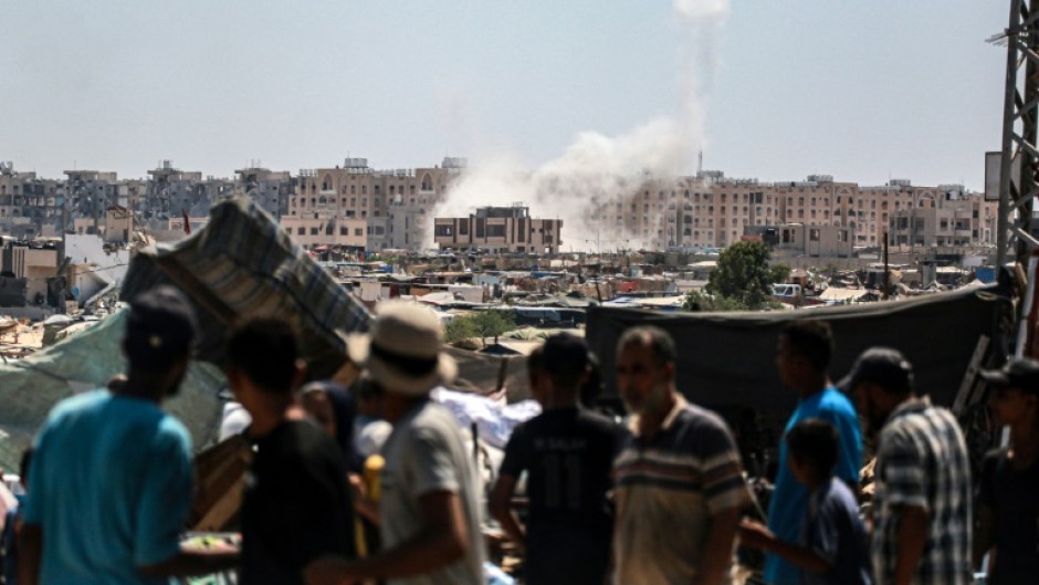 Palestinians watch from a makeshift displacement camp as Israeli shelling hits Khan Yunis in the southern Gaza Strip