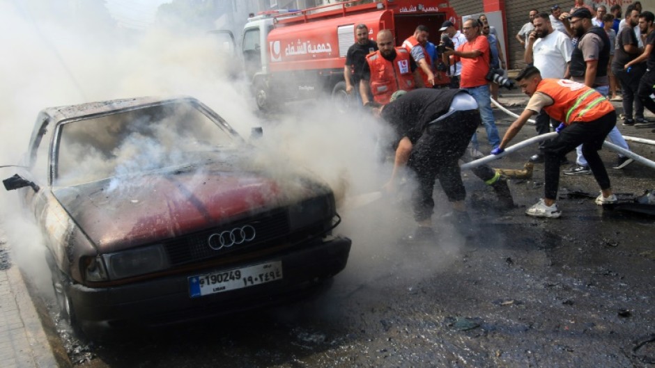 Lebanese firefighters put out a fire in a car after an Israeli strike in the southern city of Sidon on August 21, 2024