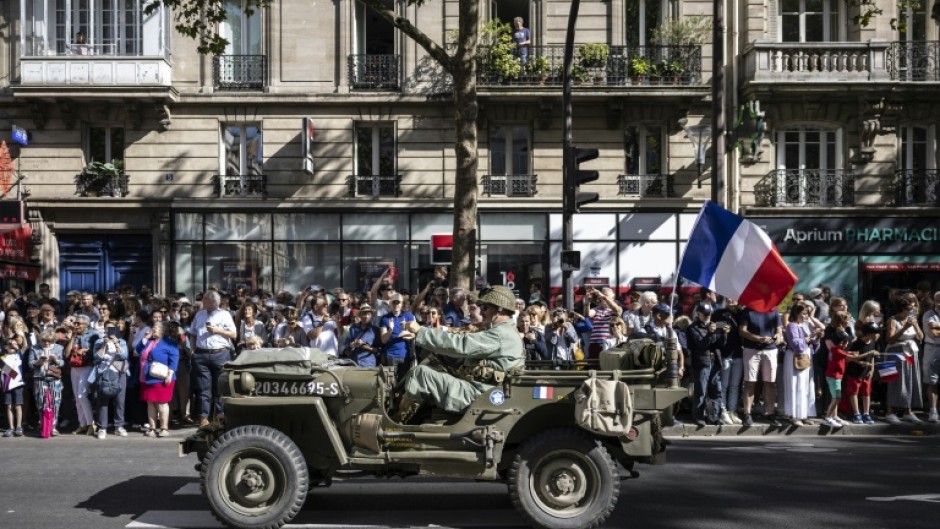 Reenactors dressed in wartime uniforms parade on wartime military vehicles during a reenactment marking the 80th anniversary of the liberation of Paris from the Germans during World War II