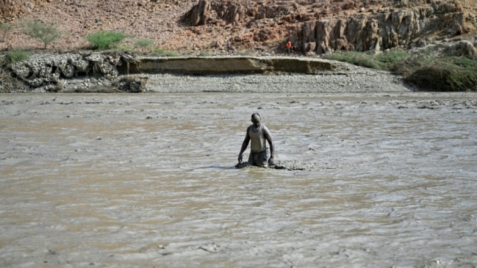 A Sudanese man wades through muddy waters after the collapse of the Arbaat Dam, 40km north of Port Sudan following heavy rains and torrential floods