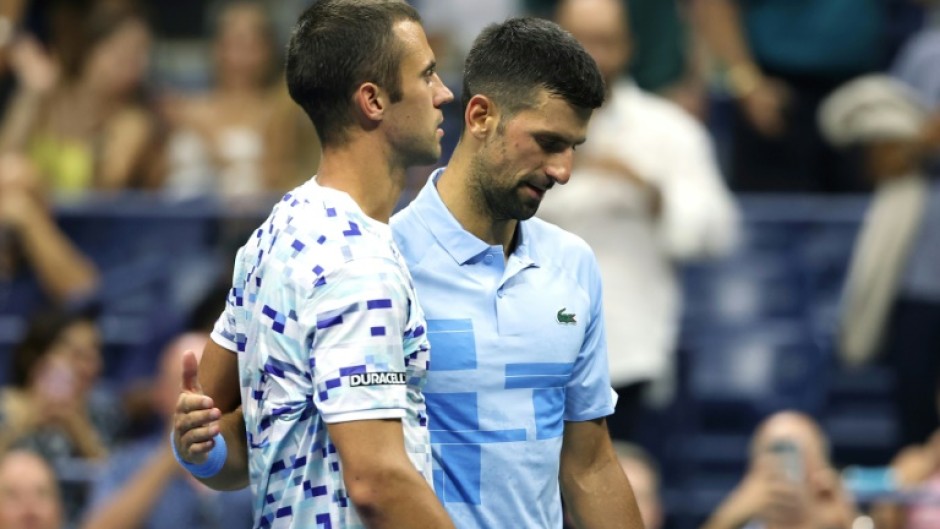 Painful end: Laslo Djere is consoled by  Novak Djokovic after being forced to retire from their second round match