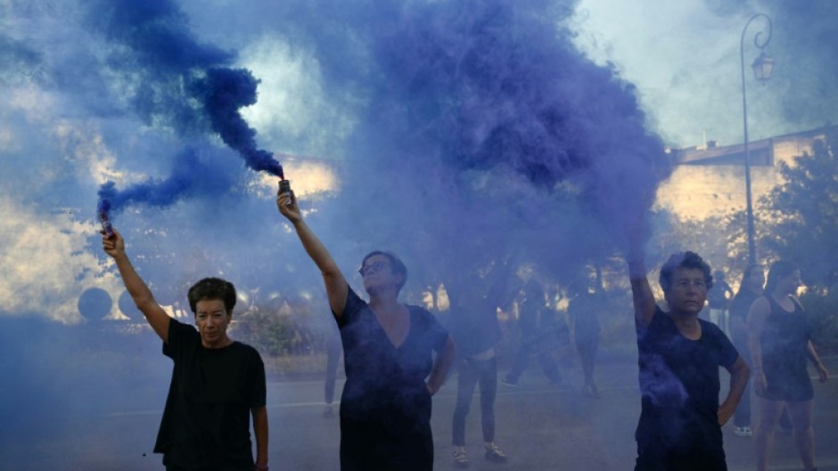 Protesters wave smoke bombs during the trial in the southern French city of Avignon of a man accused of drugging his wife Gisele Pelicot for nearly ten years and inviting strangers to rape her