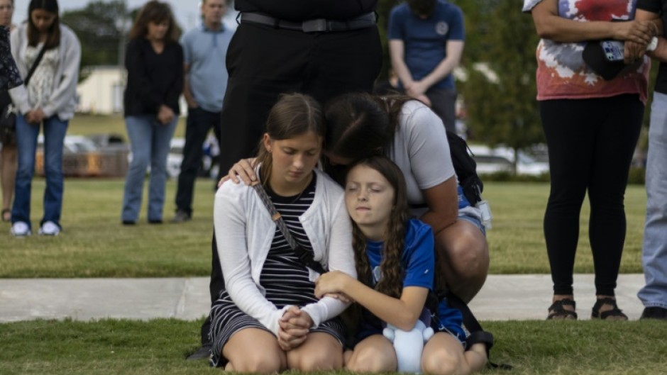 A mother and her children bow their heads in prayer at a vigil for the victims of the Apalachee High School shooting in Winder, Georgia