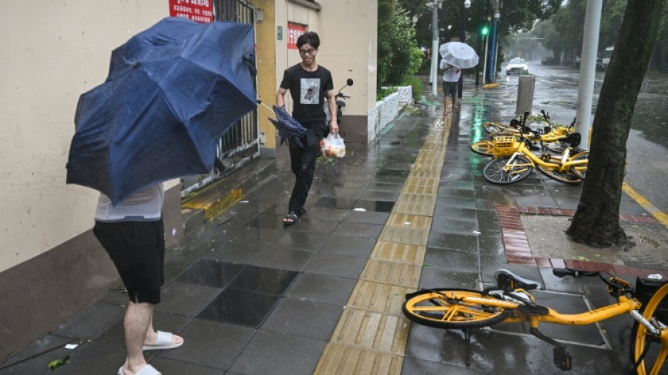 People walk past fallen bicycles amid strong winds and rain from Typhoon Bebinca