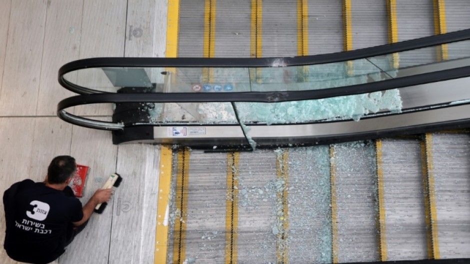 An employee at a train station in Modin, Israel, sweeps up broken glass after a missile was fired from Yemen, the military said