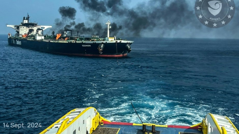 This handout picture provided by EUNAVFOR ASPIDES shows a vessel with a rope extended toward the Greek-owned oil tanker Sounion as smoke and fire billows from it, off the coast of Hodeida in the Red Sea