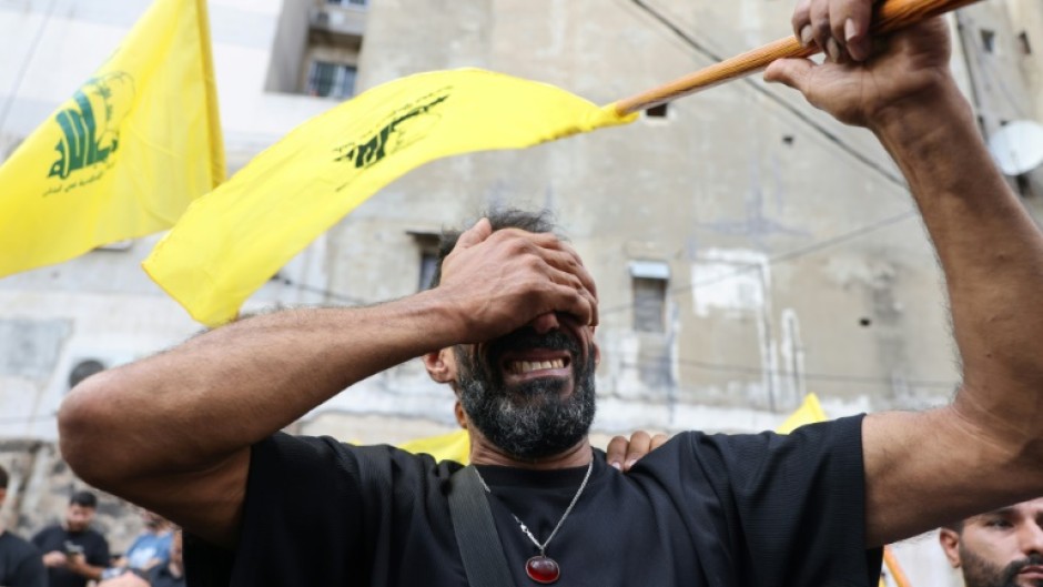 A Lebanese man clutching a Hezbollah flag is seen at funeral for people killed in pager attacks