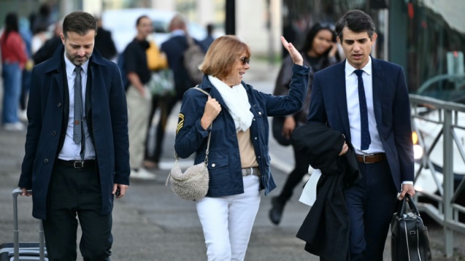 Gisele Pelicot walks with her lawyers as they arrive at the courthouse in the southeastern French city of Avignon during the trial of her former husband Dominique Pelicot accused of drugging her for nearly ten years and inviting strangers to rape her