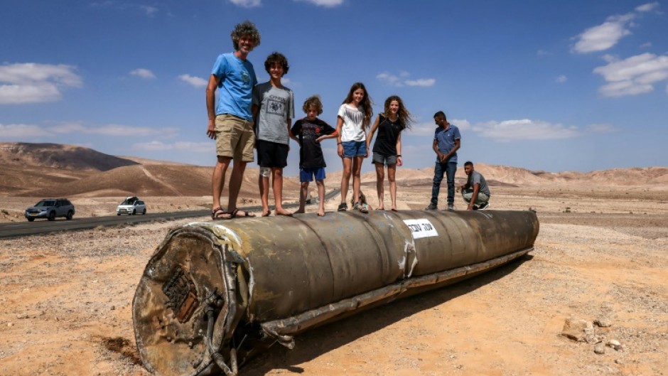 People stand on top of the remains of an Iranian missile in the Negev desert near Arad in southern Israel