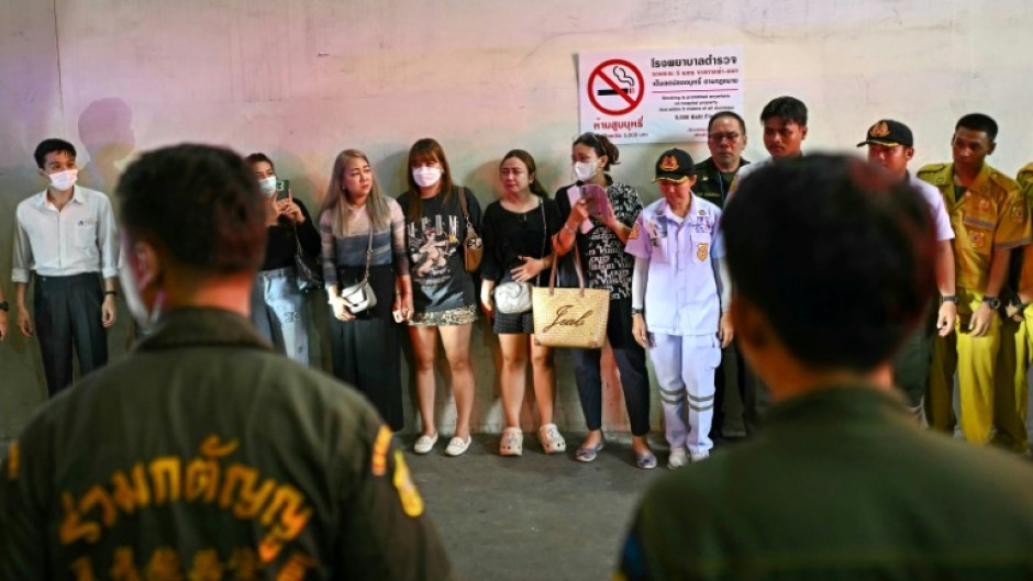 Grieving Thai relatives watch as ambulances carry the remains of victims of a school bus fire that killed 23 people, most of them children, in northern Bangkok