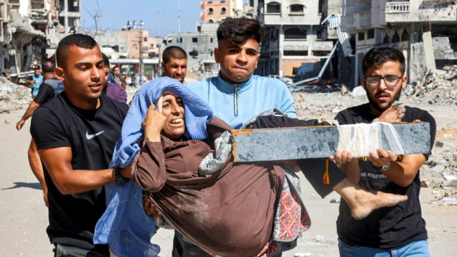 Men carry an injured woman at the Jabalia camp for Palestinian refugees in the northern Gaza which has been under siege since last weekend