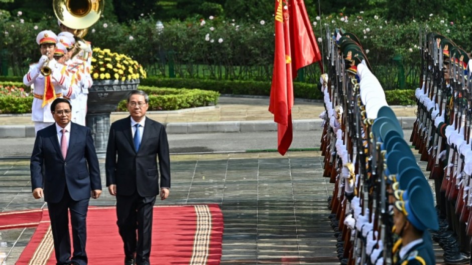 Vietnam Prime Minister Pham Minh Chinh (left) and China's Premier Li Qiang inspect a guard of honour during a welcoming ceremony at the Presidential Palace in Hanoi on October 13, 2024