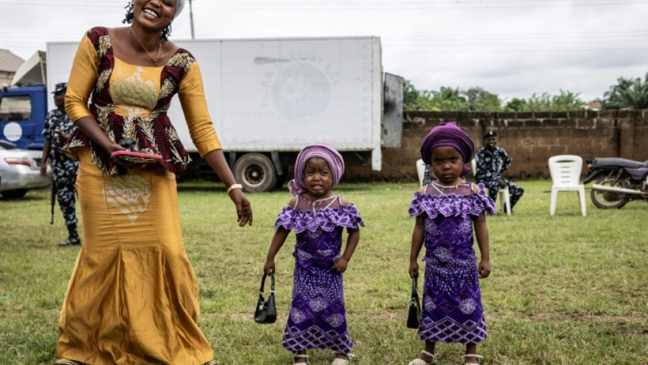 The twins paraded in immaculate matching outfits -- from glamorous sunglasses and patterned adire fabric to a pair of toddlers sporting purple dresses and identical handbags