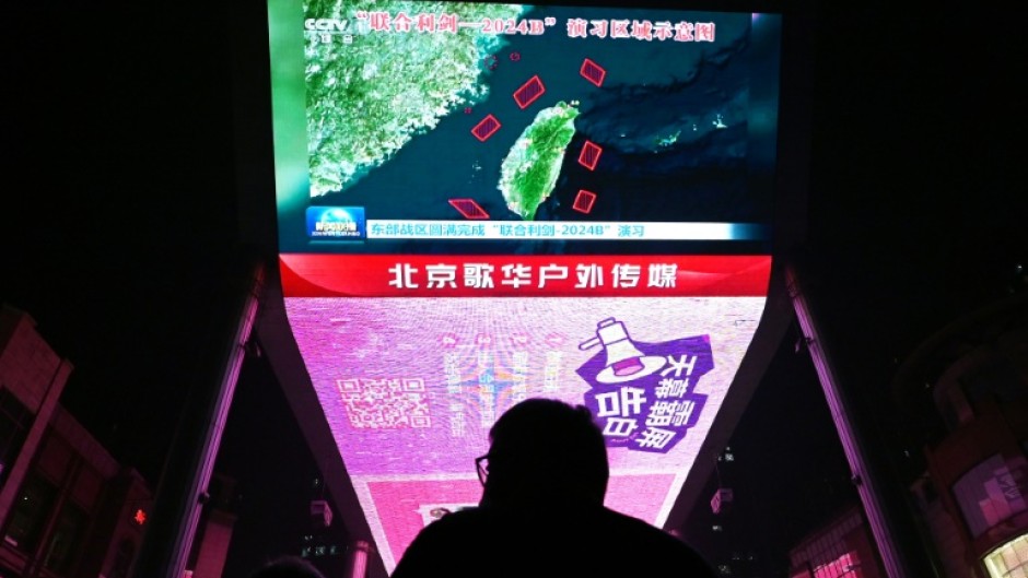 A man watches news about Chinese military drills surrounding Taiwan, on a giant screen outside a shopping mall in Beijing 