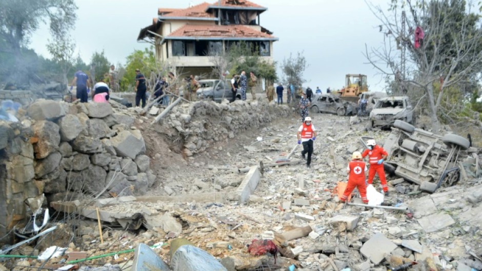 Red Cross paramedics unearth a body at the site of an Israeli air strike that targeted the northern Lebanese village of Aito