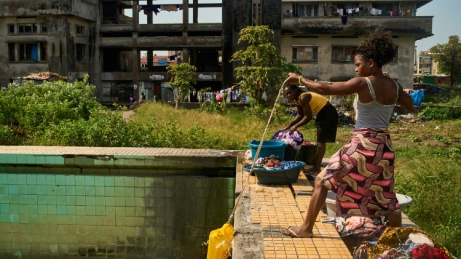 A woman uses a rope and a plastic container to get water from a pool at the Grande Hotel in Beira