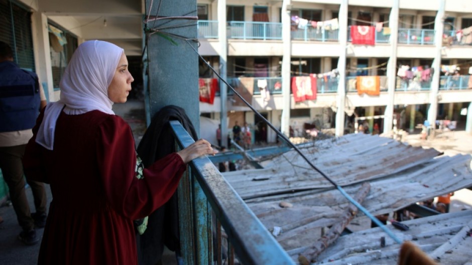 A displaced Palestinian stares from a balcony at a bombarded school-turned-shelter in northern Gaza