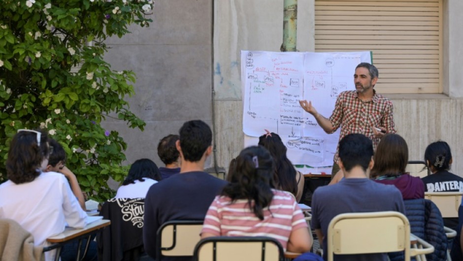 Students take a class in the street outside the faculty of philosophy and letters of the University of Buenos Aires (UBA) in Buenos Aires on October 16, 2024. Students from Argentina's public universities are protesting President Javier Milei's funding cuts